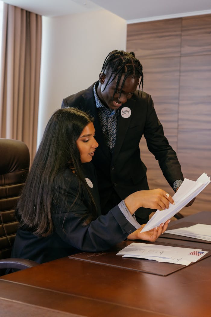 Professional adults discussing paperwork in an office setting, showcasing diversity and teamwork.